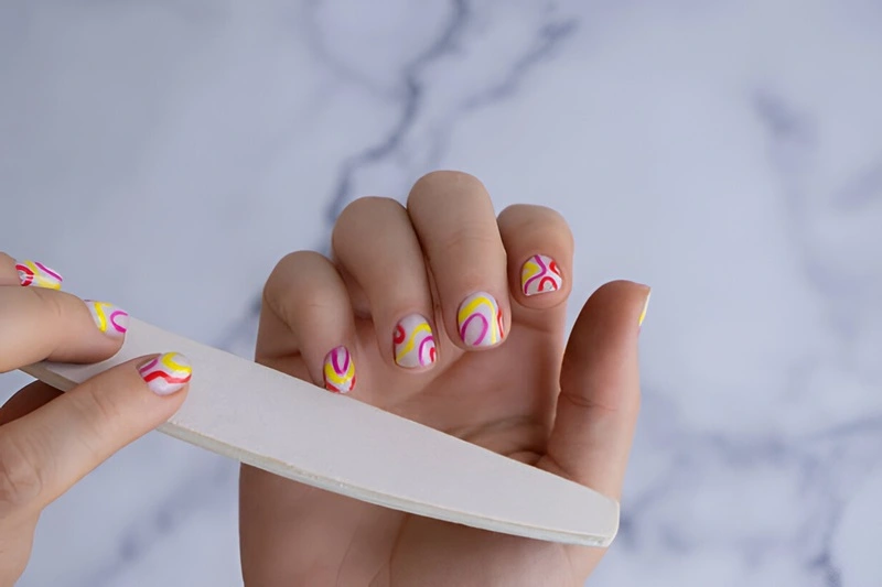 une femme nettoie ses ongles en acrylique